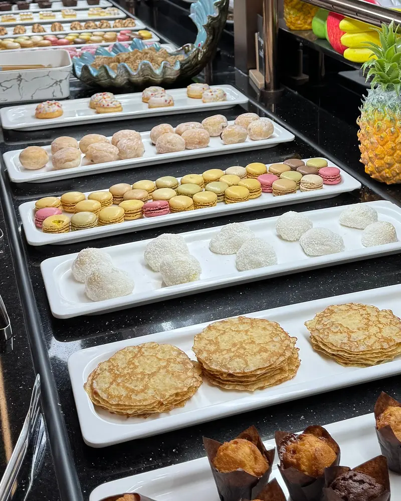 Desserts alignés au buffet : macarons, perles de coco, crêpes et muffins