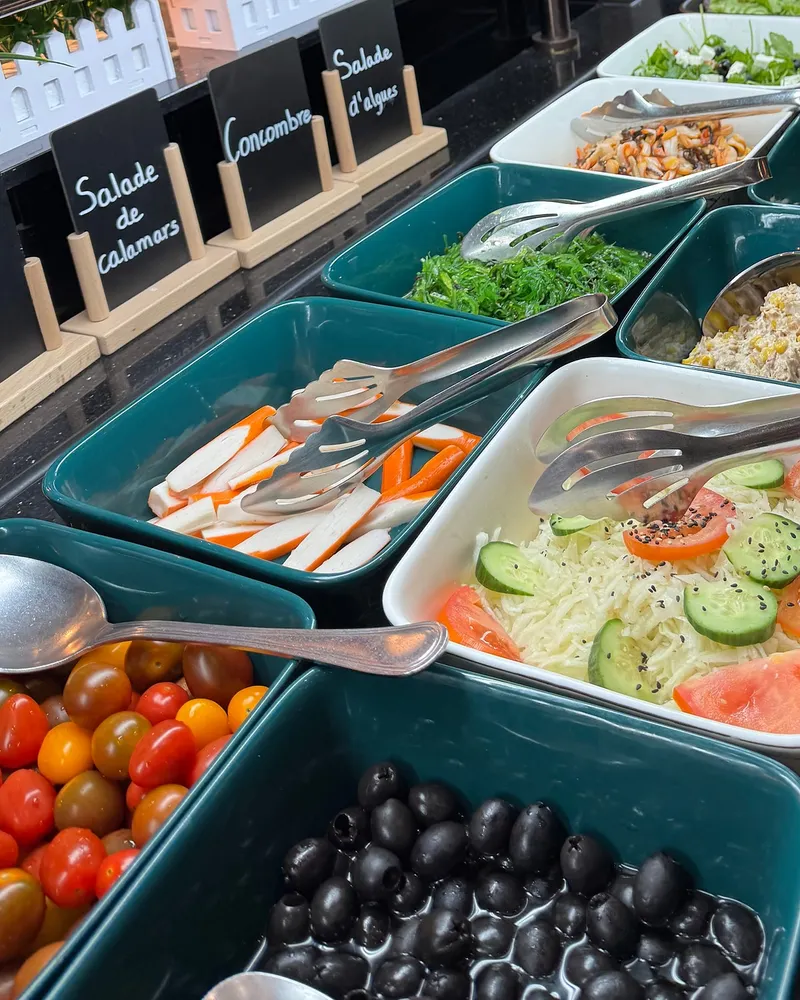 Entrées et salades au buffet : tomates cerises, olives noires, salade de chou au concombre, salade d'algues