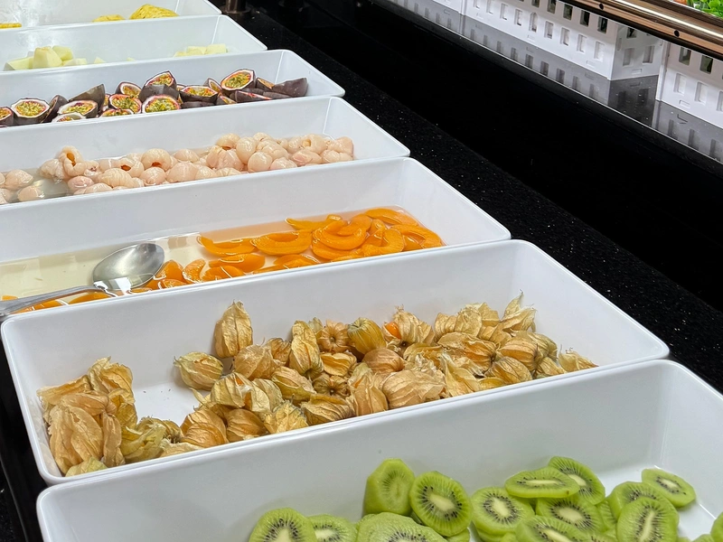 Bacs de fruits frais au buffet : kiwis en rondelles, physalis et abricots