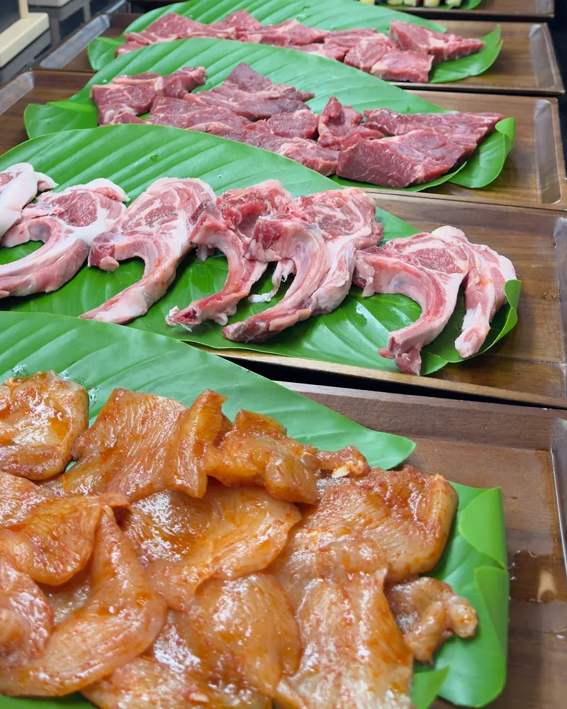 Viandes prêtes à griller sur feuilles de bananier : poulet mariné, côtelettes et tranches de bœuf